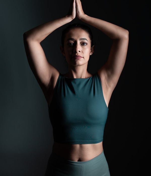 Woman in a calm yoga pose in a dark room with lime green light accents.
